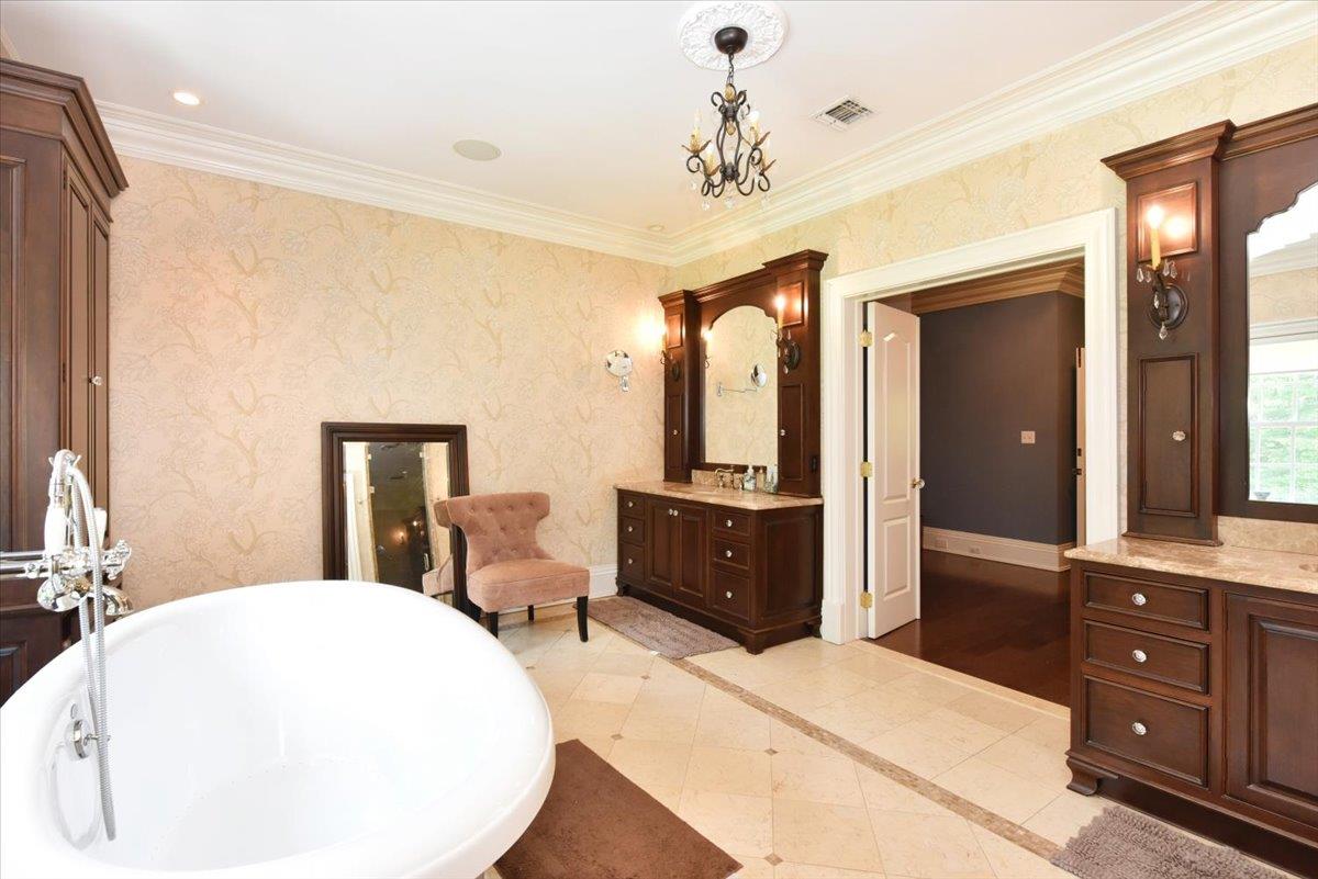 1616 Stewart Lane Syosset, NY 11791 - Photo 25 of 38 Bathroom with vanity, a freestanding bath, inlaid floor details, and crown molding