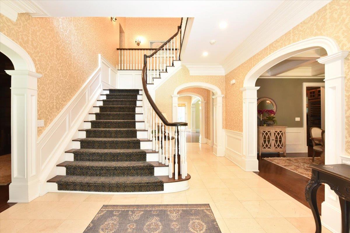 1616 Stewart Lane Syosset, NY 11791 - Photo 7 of 38 Staircase featuring arched walkways, a decorative wall, ornamental molding, wainscoting, and tile patterned floors