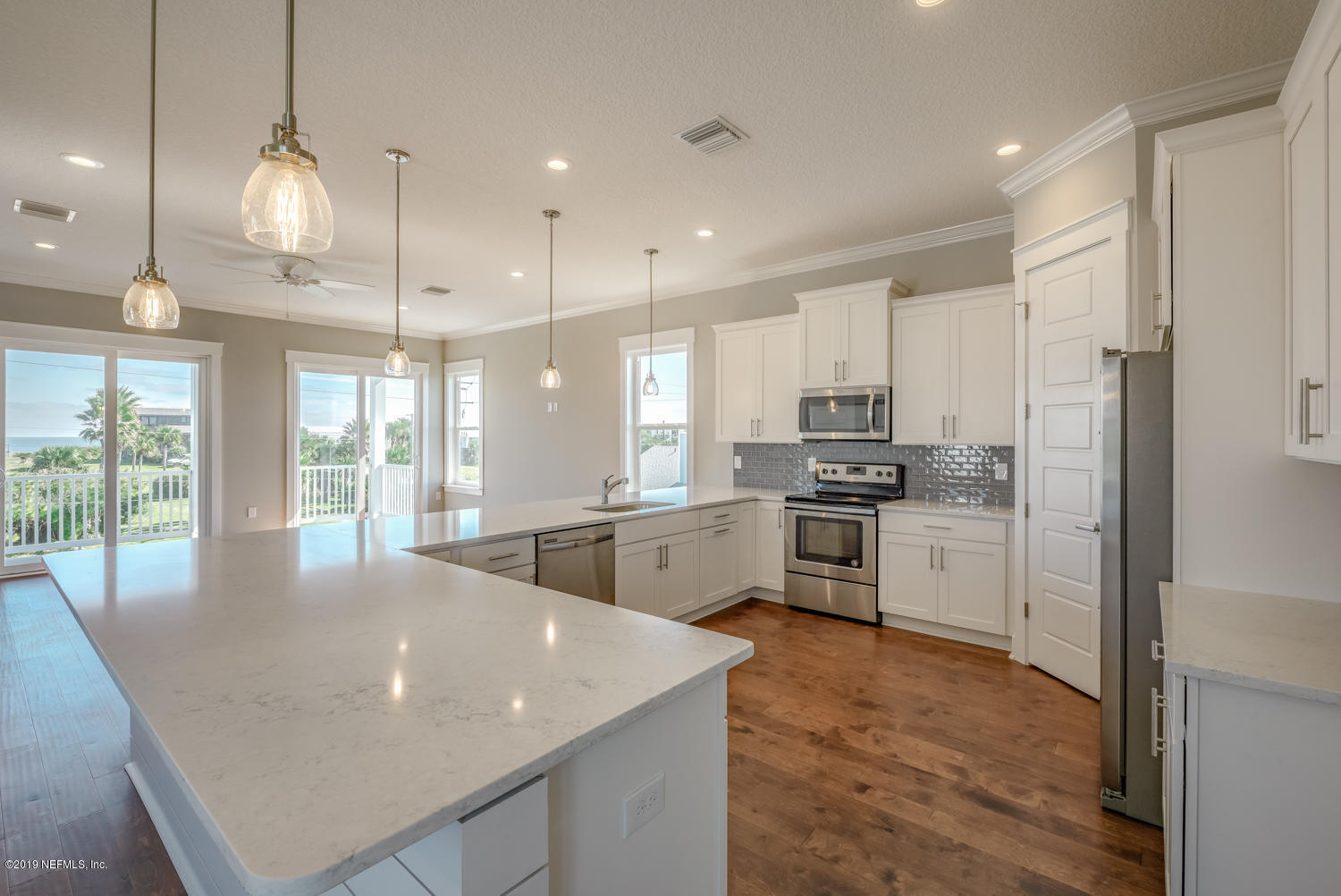 5480 Pelican Way St. Augustine, FL 32080 - Photo 3 of 4 a large kitchen with kitchen island a stove a sink a refrigerator and white cabinets with wooden floor