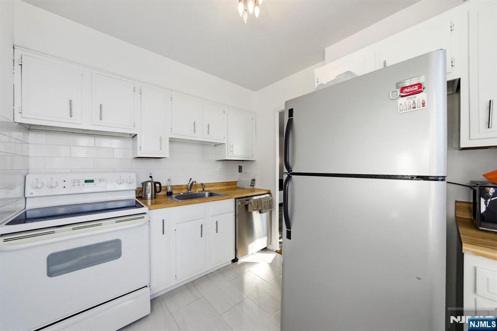 90 Prospect Avenue, Unit 8C Hackensack, NJ 07601 - Photo 9 of 29 a kitchen with stainless steel appliances granite countertop white refrigerator stove and white cabinets