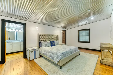 a bedroom with a bed and dresser with wooden floor