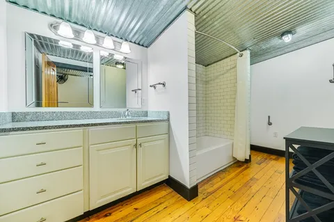 a bathroom with a granite countertop sink a mirror and shower