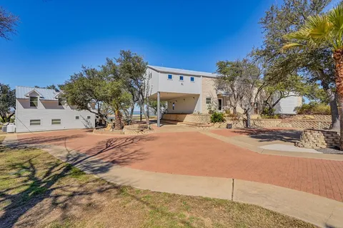 a view of a blue house with a large tree and wooden fence