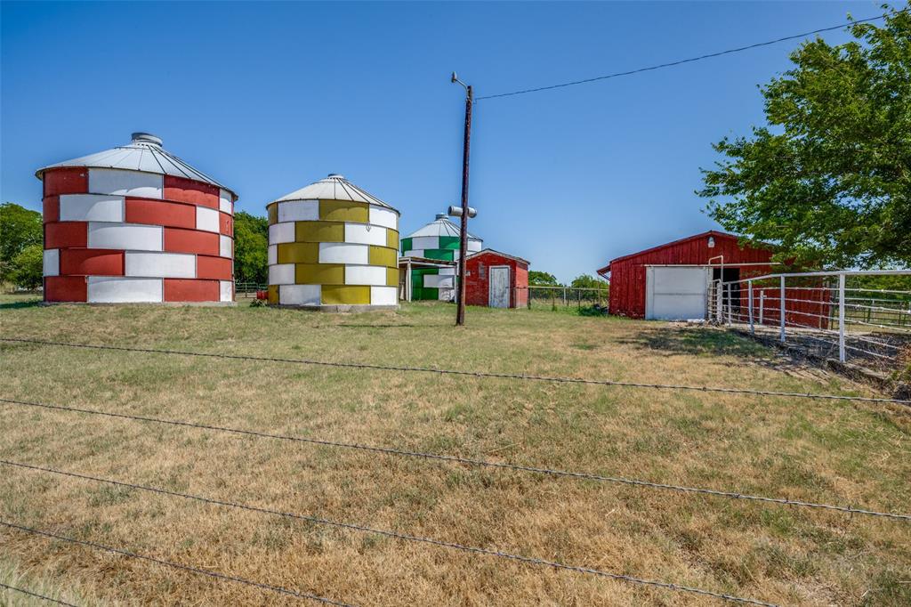 117 County Road Decatur, TX 76234 - Photo 2 of 40 Multiple colorful silos, red barn structure, and metal fencing