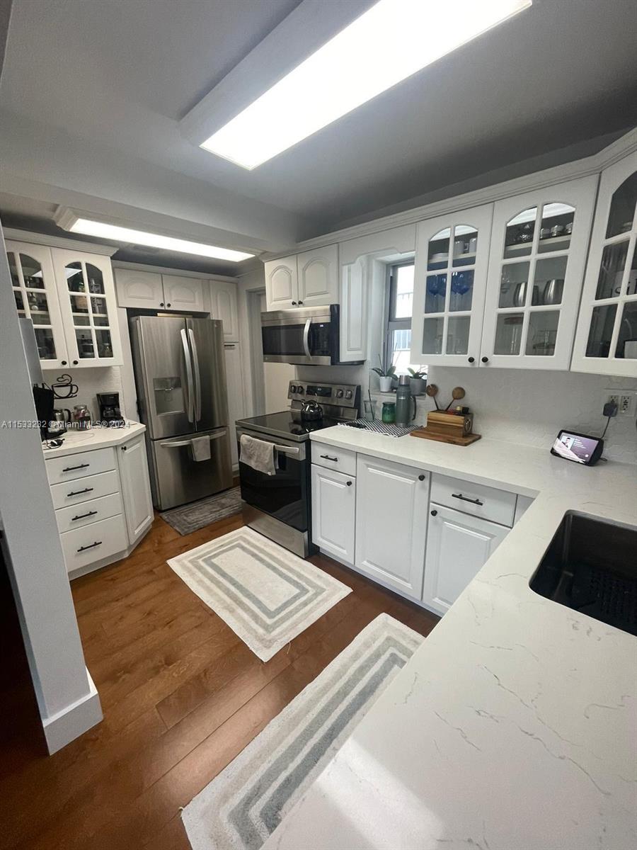 1674 Bay Road, Unit 402 Miami Beach, FL 33139 - Photo 6 of 16 a kitchen with stainless steel appliances kitchen island granite countertop a refrigerator stove top oven and sink