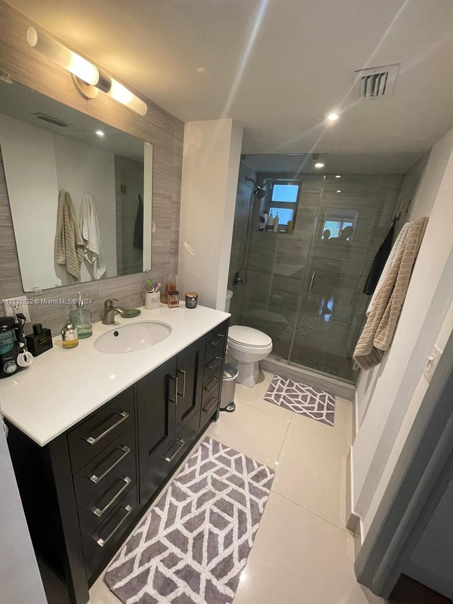 1674 Bay Road, Unit 402 Miami Beach, FL 33139 - Photo 8 of 16 a spacious bathroom with a sink mirror vanity and toilet