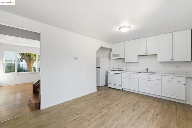 a kitchen with granite countertop white cabinets and white appliances