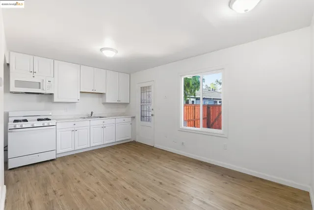 a kitchen with granite countertop white cabinets a sink a window and stainless steel appliances