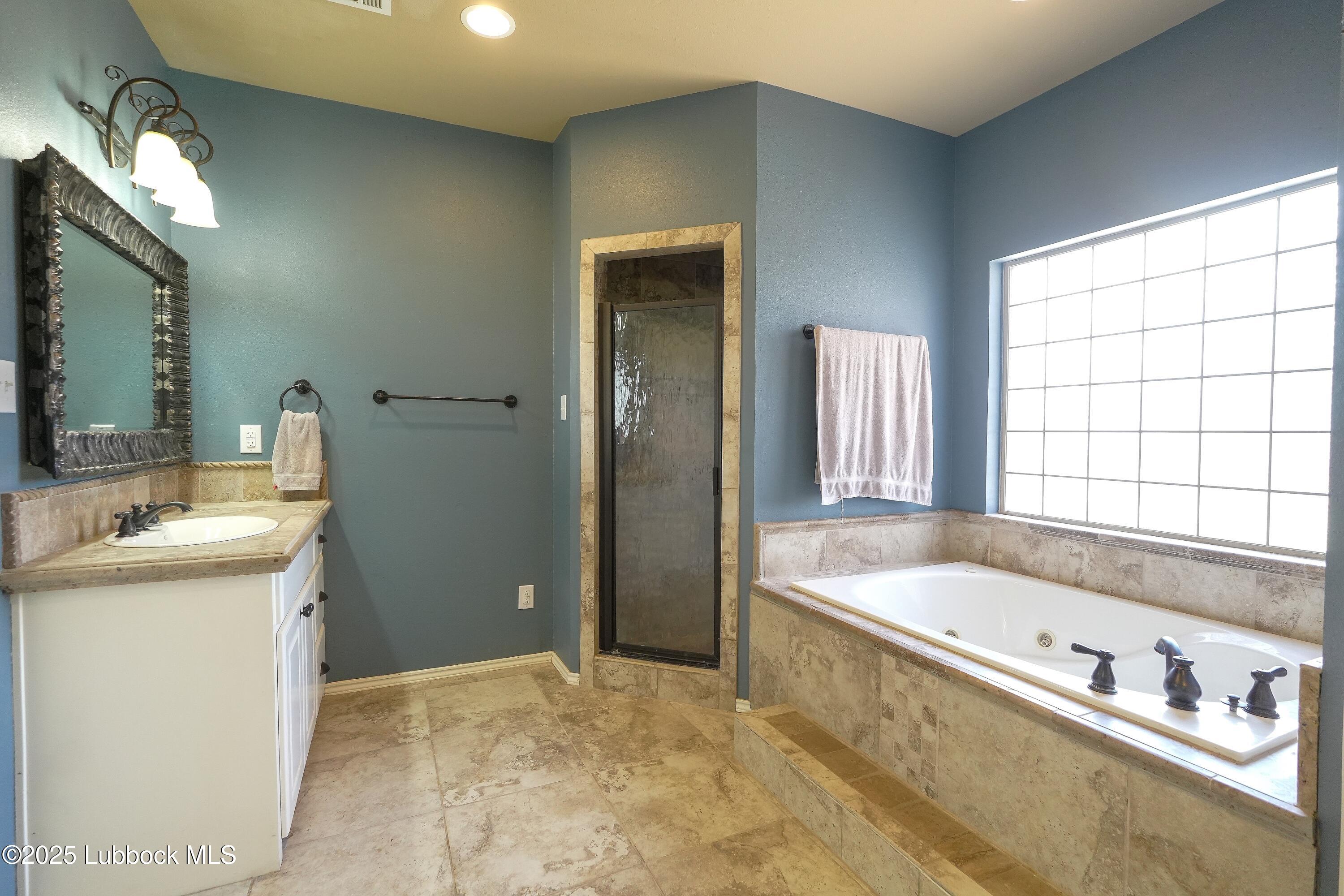 5904 110th Street Lubbock, TX 79424 - Photo 16 of 32 a bathroom with a tub a sink and a large mirror