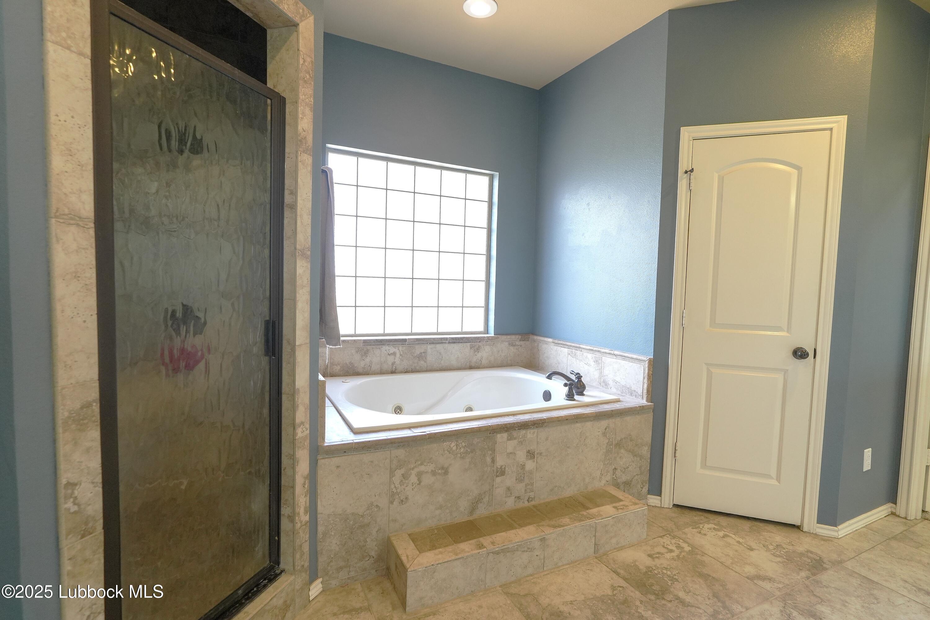 5904 110th Street Lubbock, TX 79424 - Photo 18 of 32 a bathroom with a tub a sink and a window