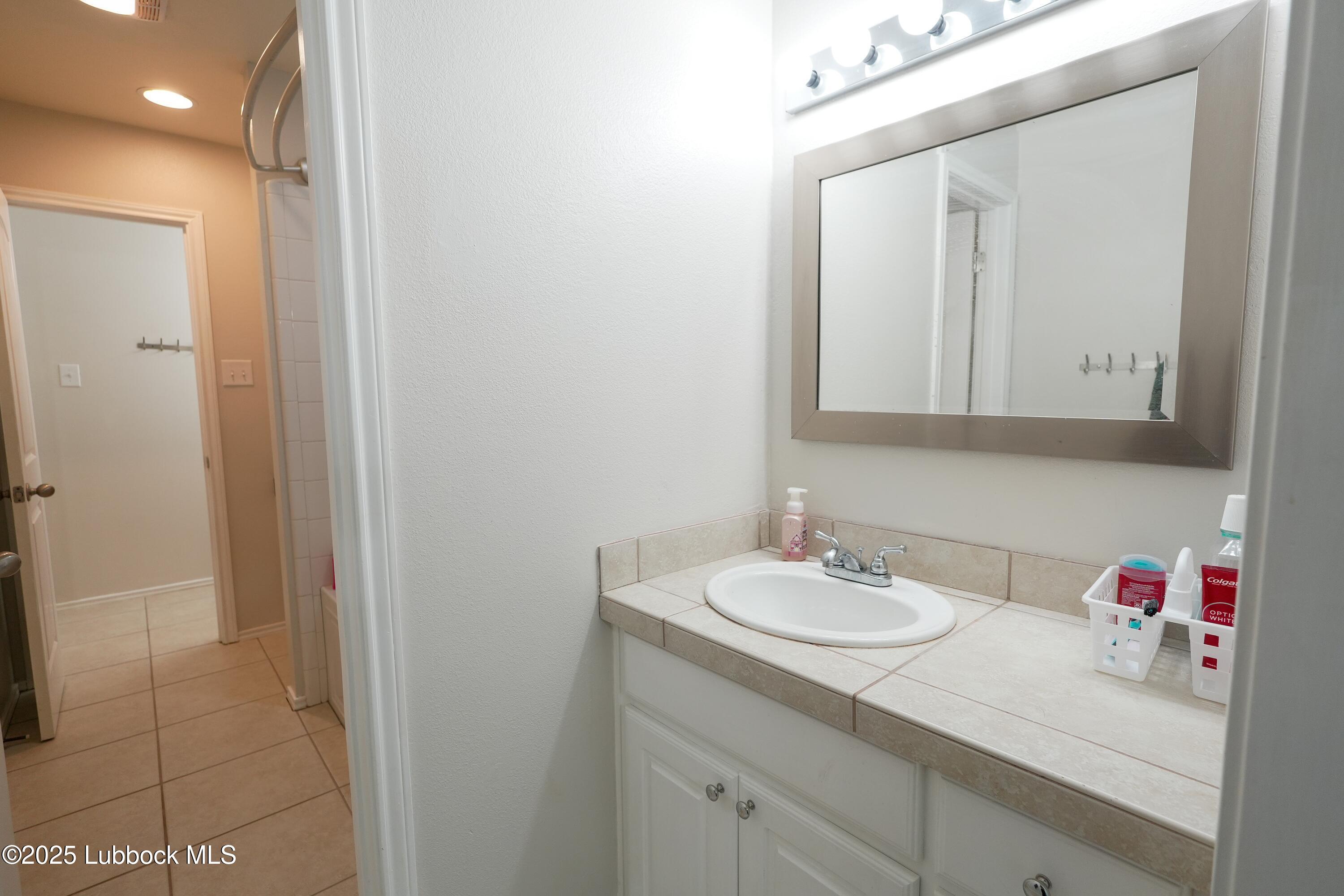 5904 110th Street Lubbock, TX 79424 - Photo 23 of 32 a bathroom with a sink vanity and a mirror