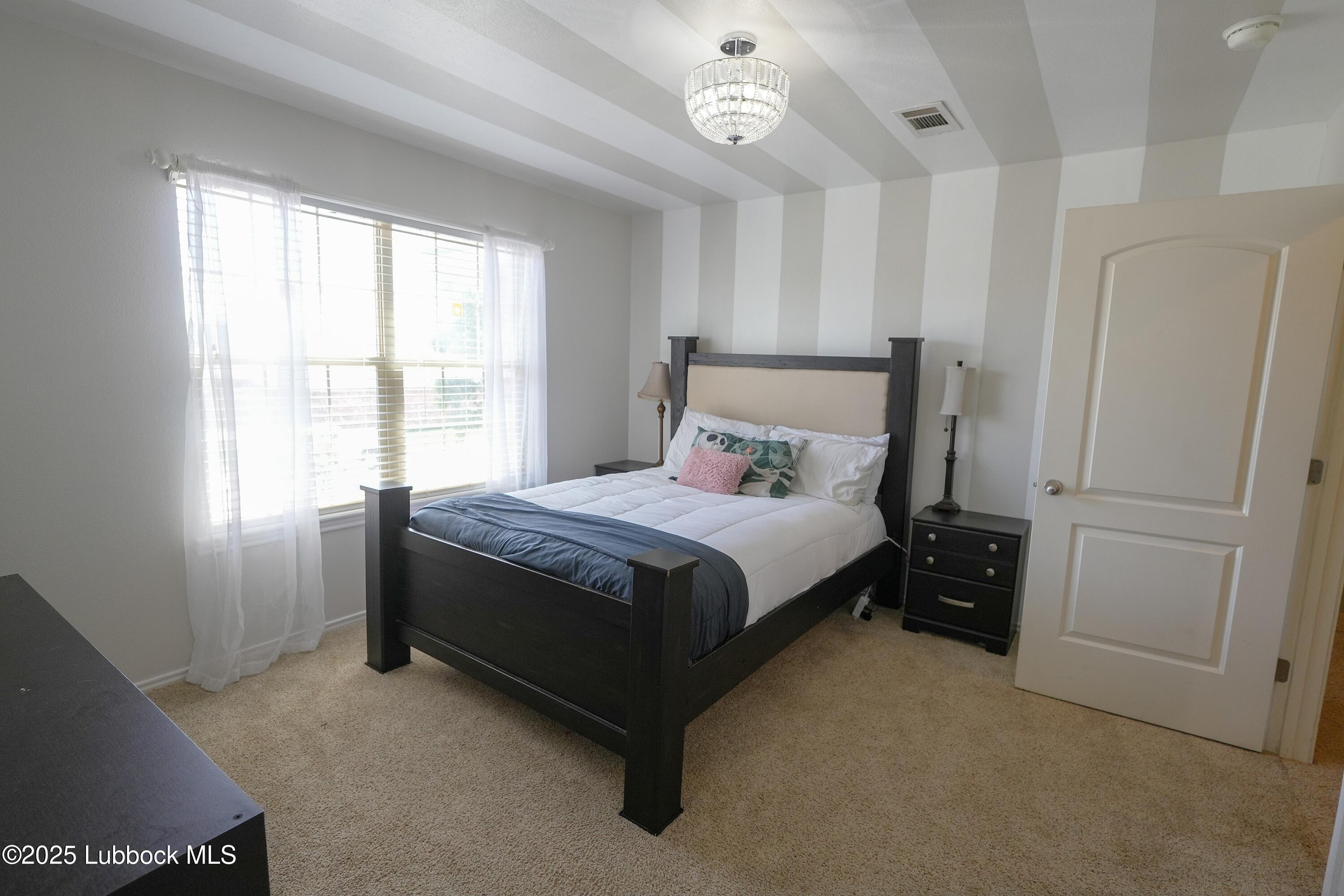 5904 110th Street Lubbock, TX 79424 - Photo 24 of 32 a bed sitting in a bedroom next to a window