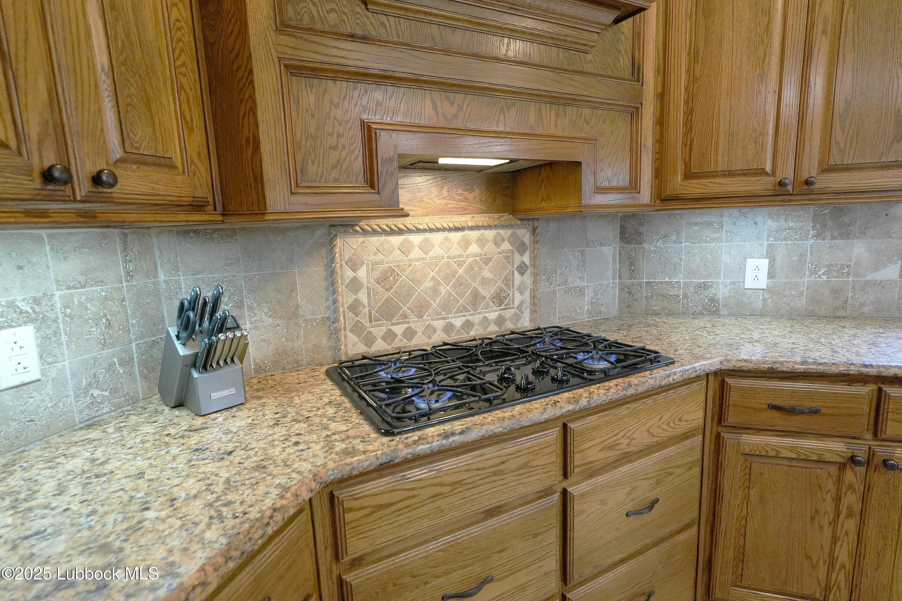 5904 110th Street Lubbock, TX 79424 - Photo 8 of 32 a kitchen with granite countertop cabinets and a stove top oven