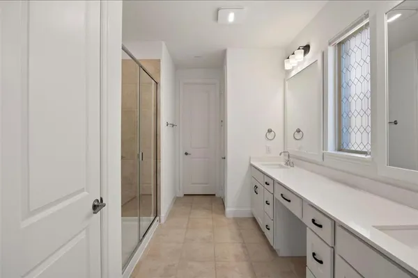 a spacious bathroom with a double vanity sink a mirror and a shower