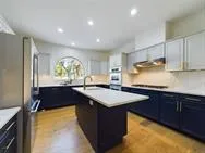 a kitchen with kitchen island granite countertop a sink a counter top space and stainless steel appliances