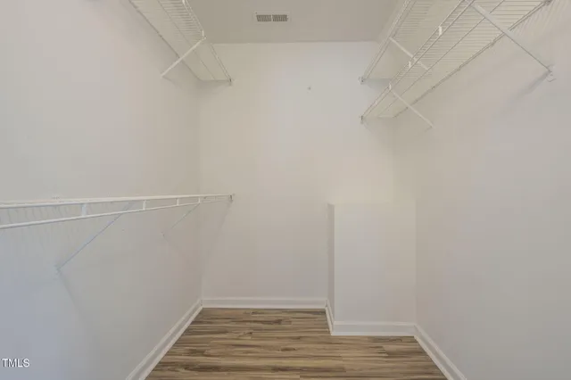 an empty room with wooden floor chandelier fan and windows