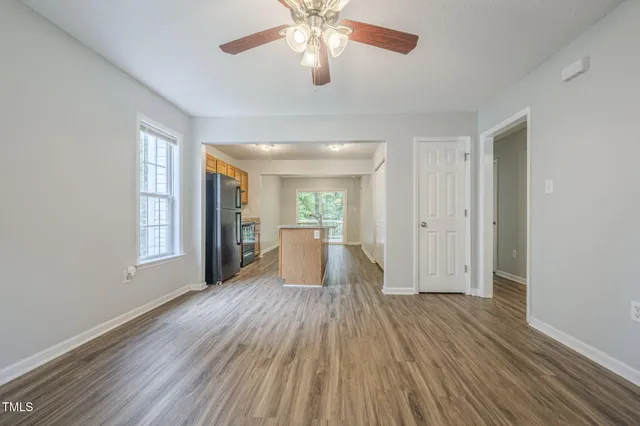 an empty room with wooden floor windows and fan