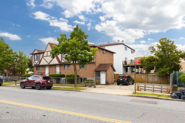 a view of a brick house with a fountain and a large tree