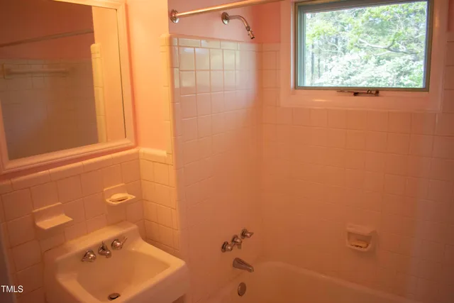 a bathroom with a tub sink and mirror