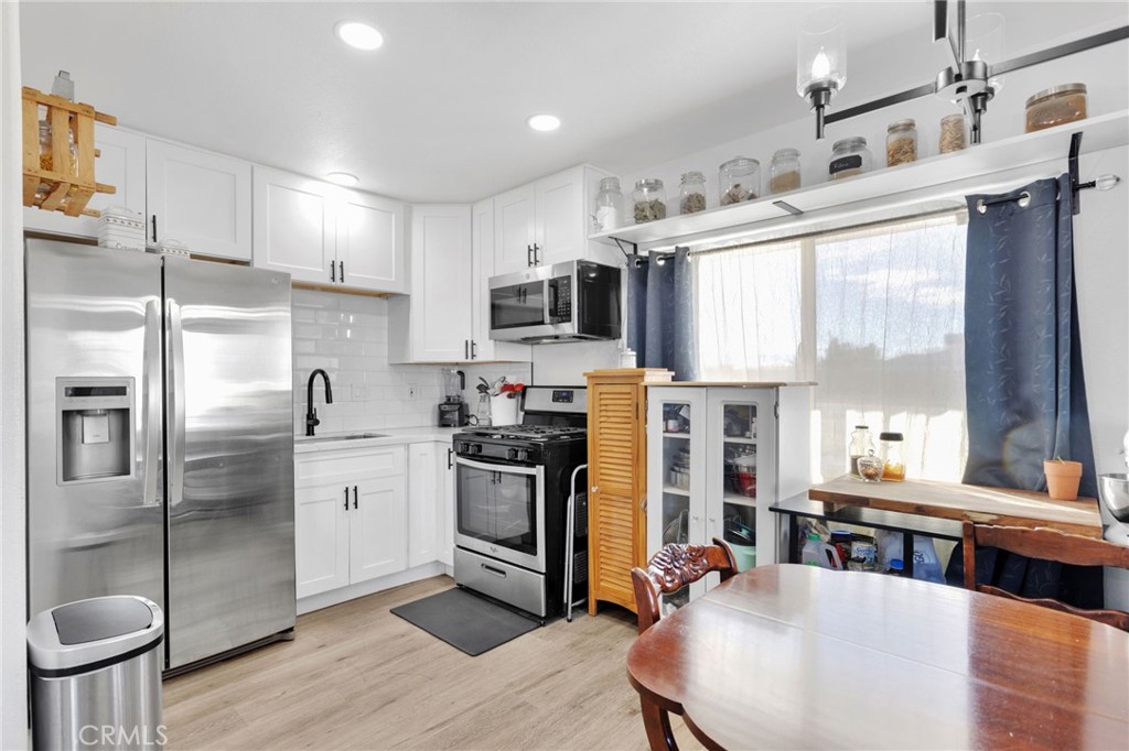 15109 Anacapa Road Victorville, CA 92392 - Photo 16 of 40 a kitchen with stainless steel appliances granite countertop a refrigerator a stove a sink dishwasher and white cabinets with wooden floor