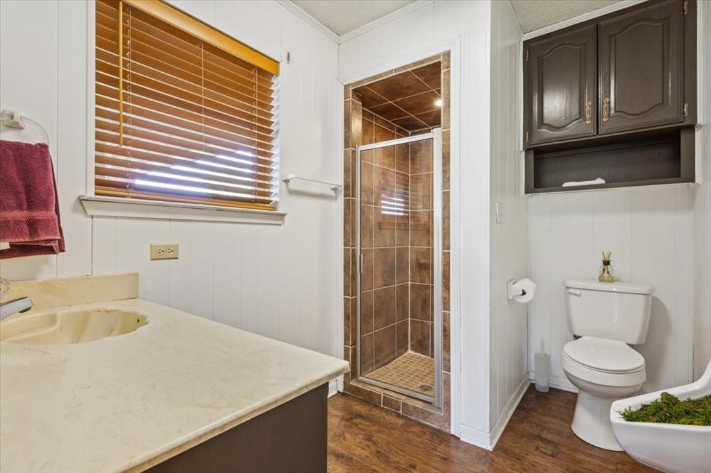 221 County Road 157 Riesel, TX 76682 - Photo 24 of 30 Bathroom featuring toilet, a stall shower, wood finished floors, vanity, and crown molding