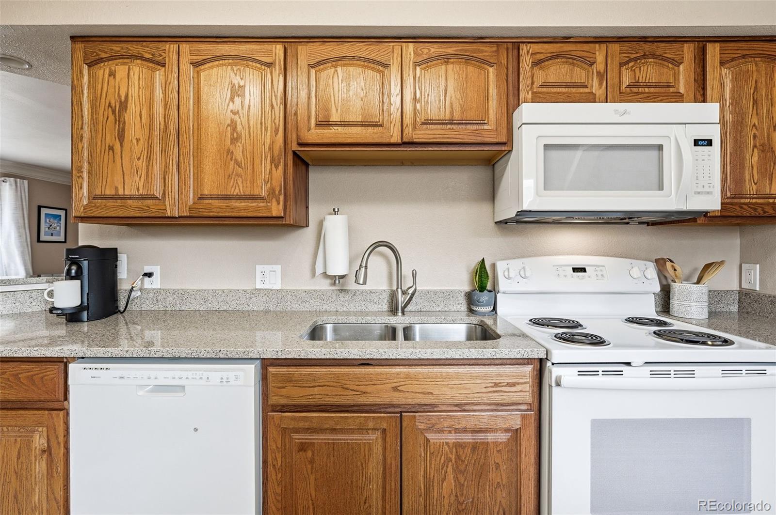 9280 Wigham Street Thornton, CO 80229 - Photo 12 of 34 a kitchen with granite countertop a sink and a stove top oven