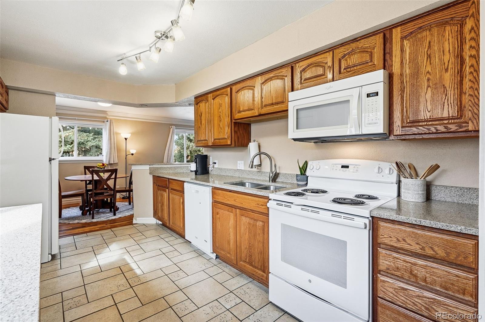 9280 Wigham Street Thornton, CO 80229 - Photo 14 of 34 a kitchen with stainless steel appliances granite countertop a stove sink and cabinets