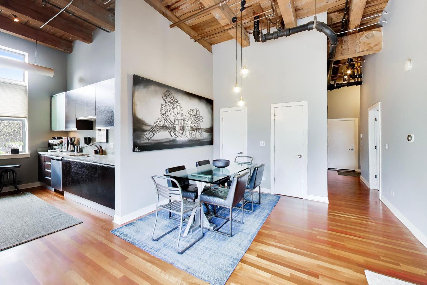 1050 West Hubbard Street, Unit 2F Chicago, IL 60642 - Photo 8 of 33 a dining room with wooden floor a chandelier a wooden table and chairs