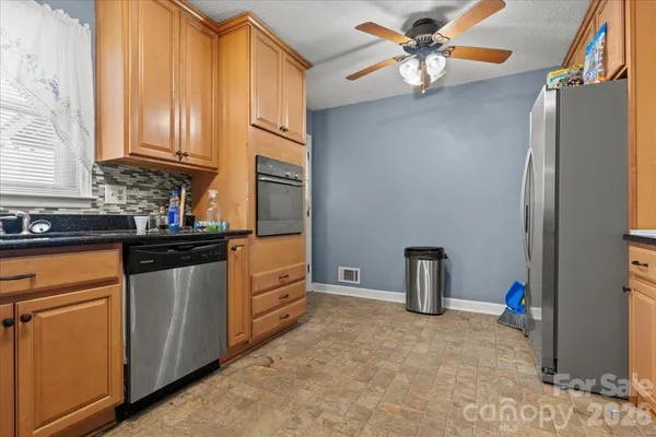 a kitchen with stainless steel appliances granite countertop a refrigerator a stove and a sink with cabinets