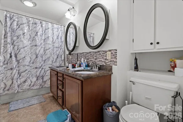 a bathroom with a granite countertop toilet a sink and a mirror