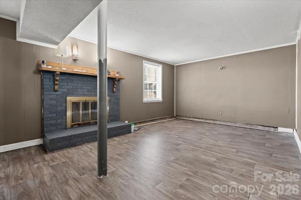 a view of empty room with wooden floor and fireplace