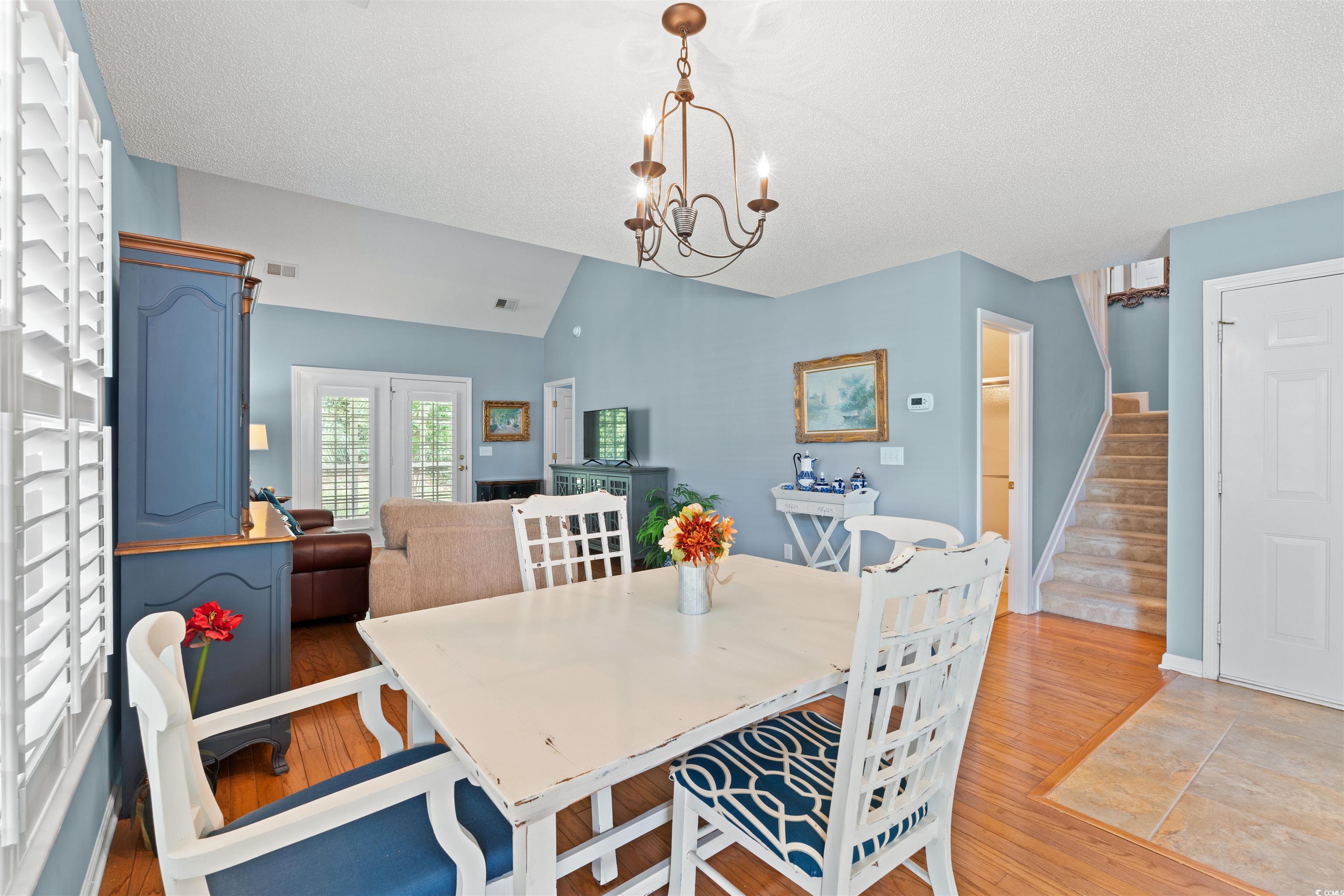 168 Wimbledon Way, Unit 168 Murrells Inlet, SC 29576 - Photo 3 of 27 Dining space with lofted ceiling, light wood-style floors, stairs, a chandelier, and a textured ceiling