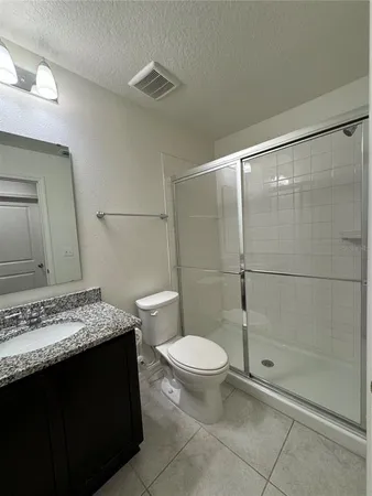 a bathroom with a granite countertop sink a toilet and shower