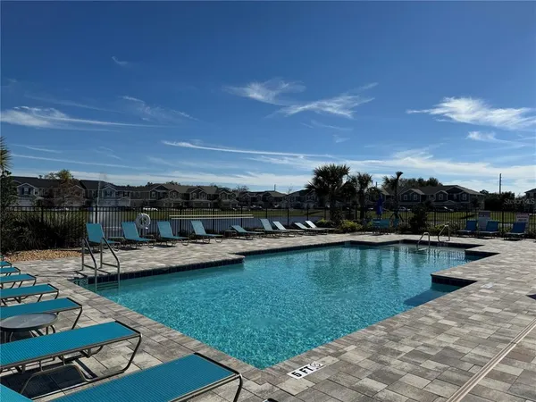 a view of swimming pool with lawn chairs and a yard