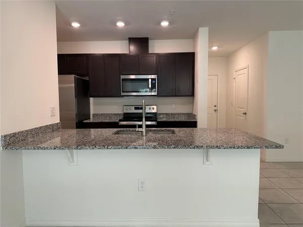 a kitchen with stainless steel appliances granite countertop a sink a stove and a refrigerator