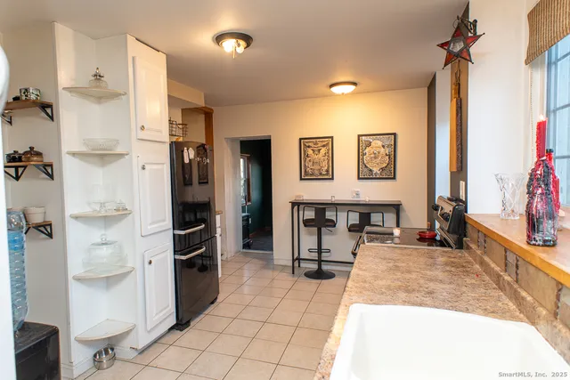 a living room with stainless steel appliances furniture a refrigerator and a dining table