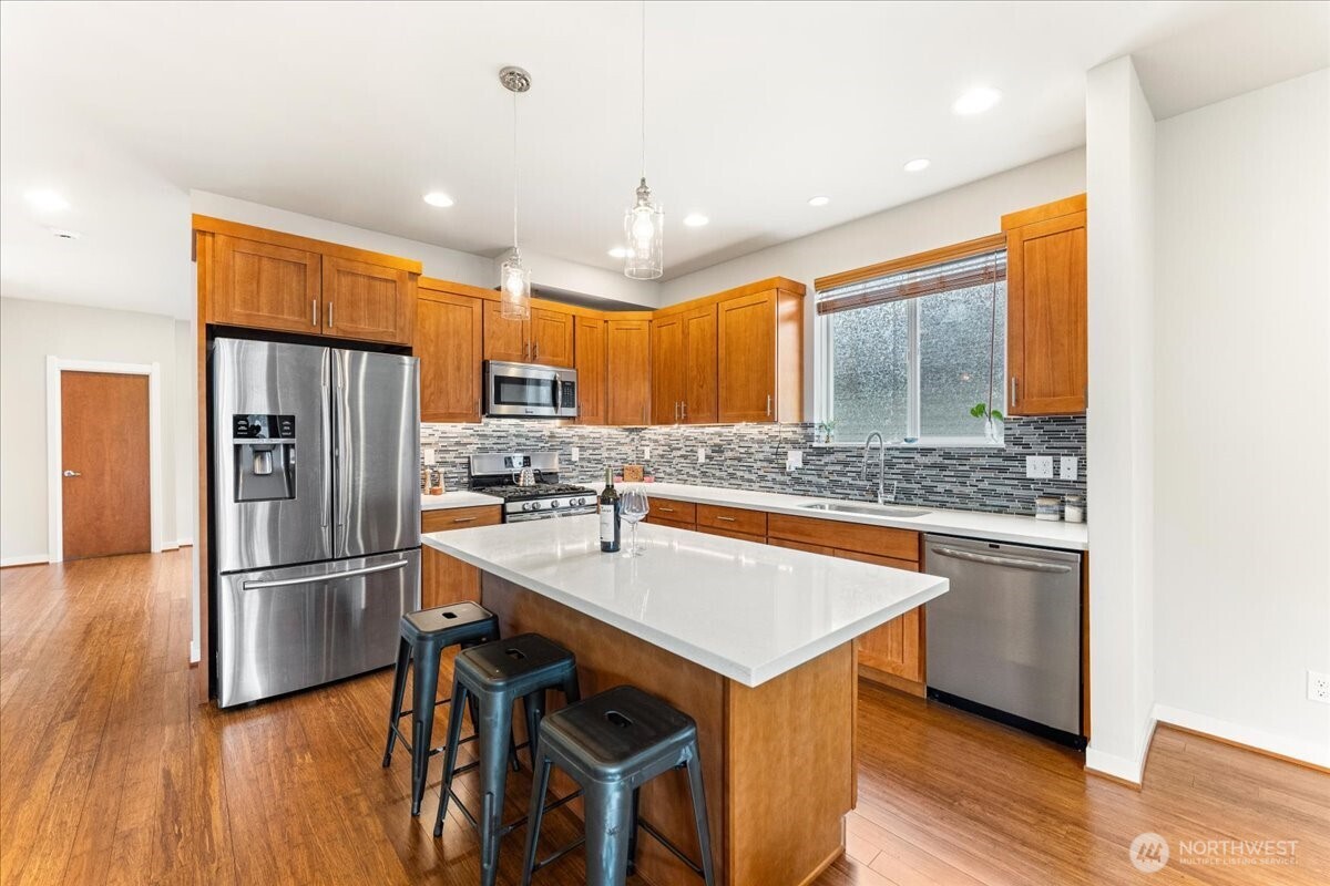 12418 2nd Place Southwest Burien, WA 98146 - Photo 7 of 39 a kitchen with stainless steel appliances granite countertop a refrigerator a sink dishwasher a stove and white countertops with wooden floor