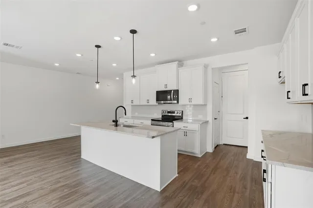 a living room with stainless steel appliances furniture a fireplace a flat screen tv and a view of kitchen