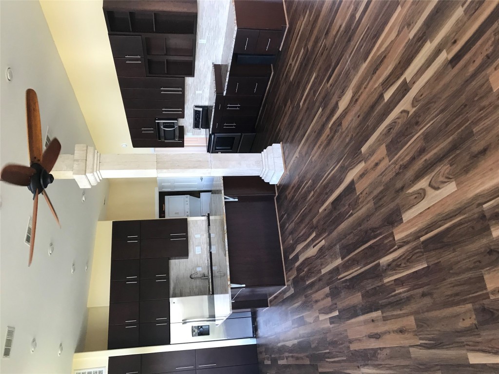 19600 Bee Creek Tavern Road, Unit B Spicewood, TX 78669 - Photo 6 of 13 a large kitchen with stainless steel appliances kitchen island granite countertop a sink dishwasher a stove and white cabinets with wooden floor