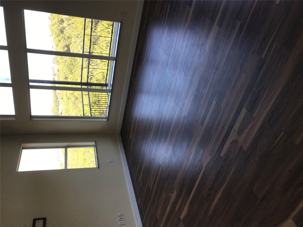 19600 Bee Creek Tavern Road, Unit B Spicewood, TX 78669 - Photo 7 of 13 an empty room with wooden floor and windows