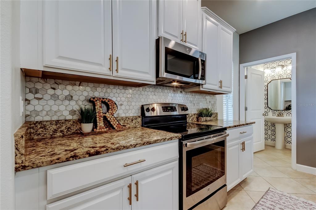 10141 Newminster Loop Ruskin, FL 33573 - Photo 28 of 77 a kitchen with granite countertop white cabinets and stainless steel appliances