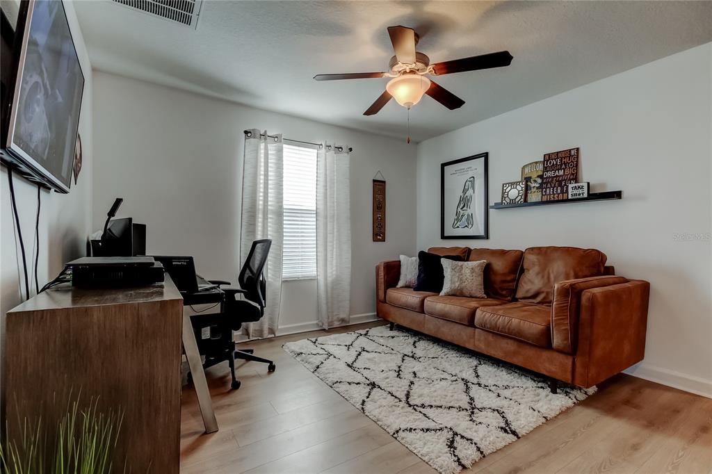 10141 Newminster Loop Ruskin, FL 33573 - Photo 47 of 77 a living room with furniture a ceiling fan and a flat screen tv