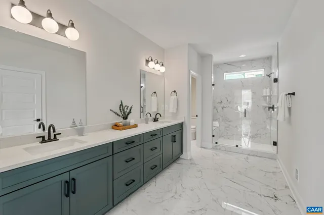 a spacious en suite bathroom with double sink and mirrors