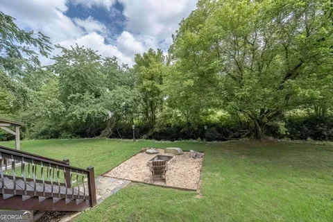 a view of a wooden house with a yard and large tree