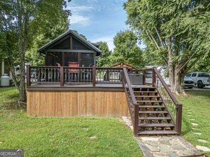 a view of a house with wooden deck and a big yard