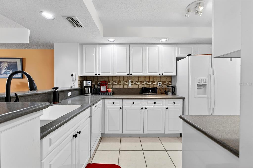 4670 Links Village Drive, Unit D506 Ponce Inlet, FL 32127 - Photo 14 of 60 a kitchen with granite countertop white cabinets and stainless steel appliances