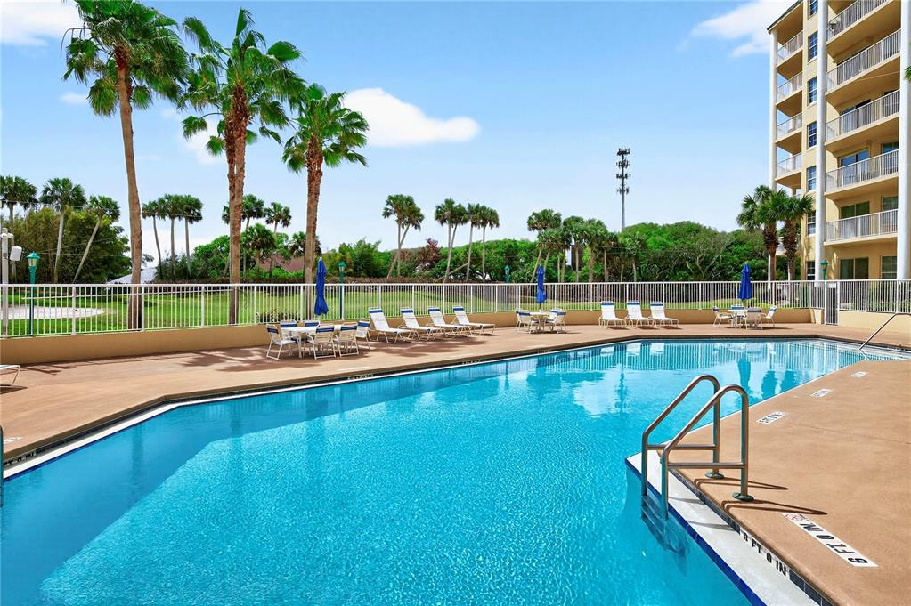 4670 Links Village Drive, Unit D506 Ponce Inlet, FL 32127 - Photo 44 of 60 a view of a swimming pool with a lawn chairs and palm tree