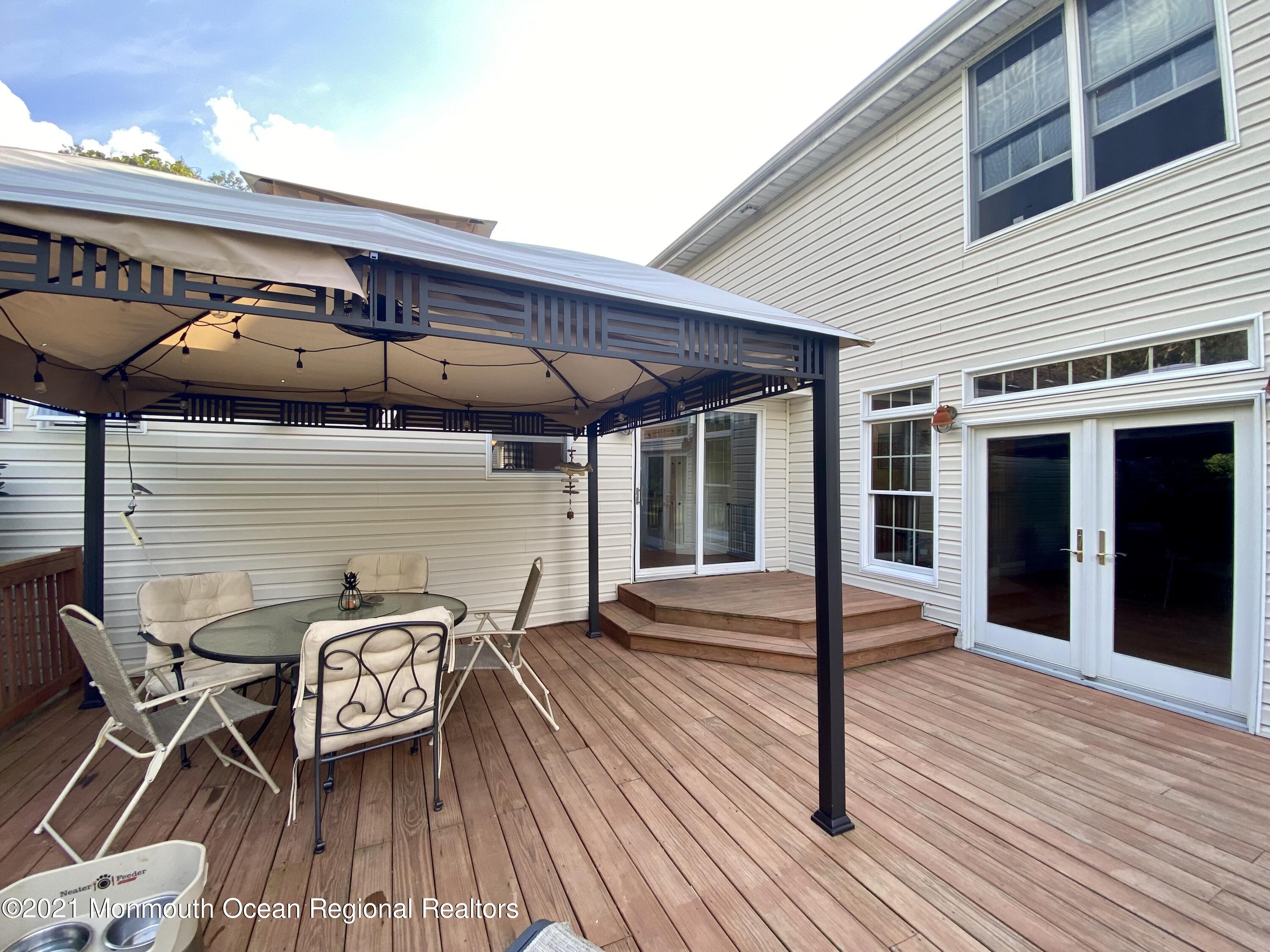 390 Cobain Road Jackson, NJ 08527 - Photo 40 of 53 a roof deck with table and chairs under an umbrella