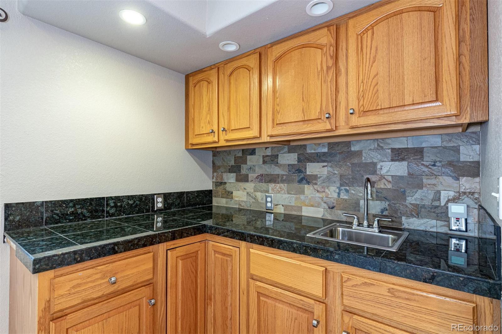 9939 Clyde Circle Highlands Ranch, CO 80129 - Photo 35 of 37 a kitchen with granite countertop a sink and cabinets