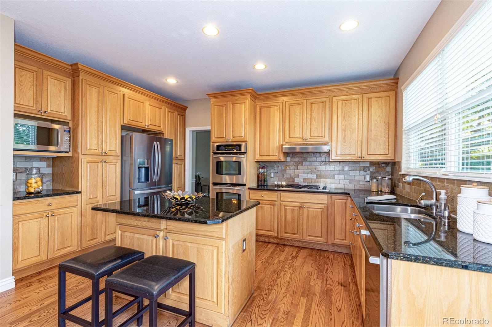 9939 Clyde Circle Highlands Ranch, CO 80129 - Photo 10 of 37 a kitchen with stainless steel appliances granite countertop sink stove refrigerator and cabinets